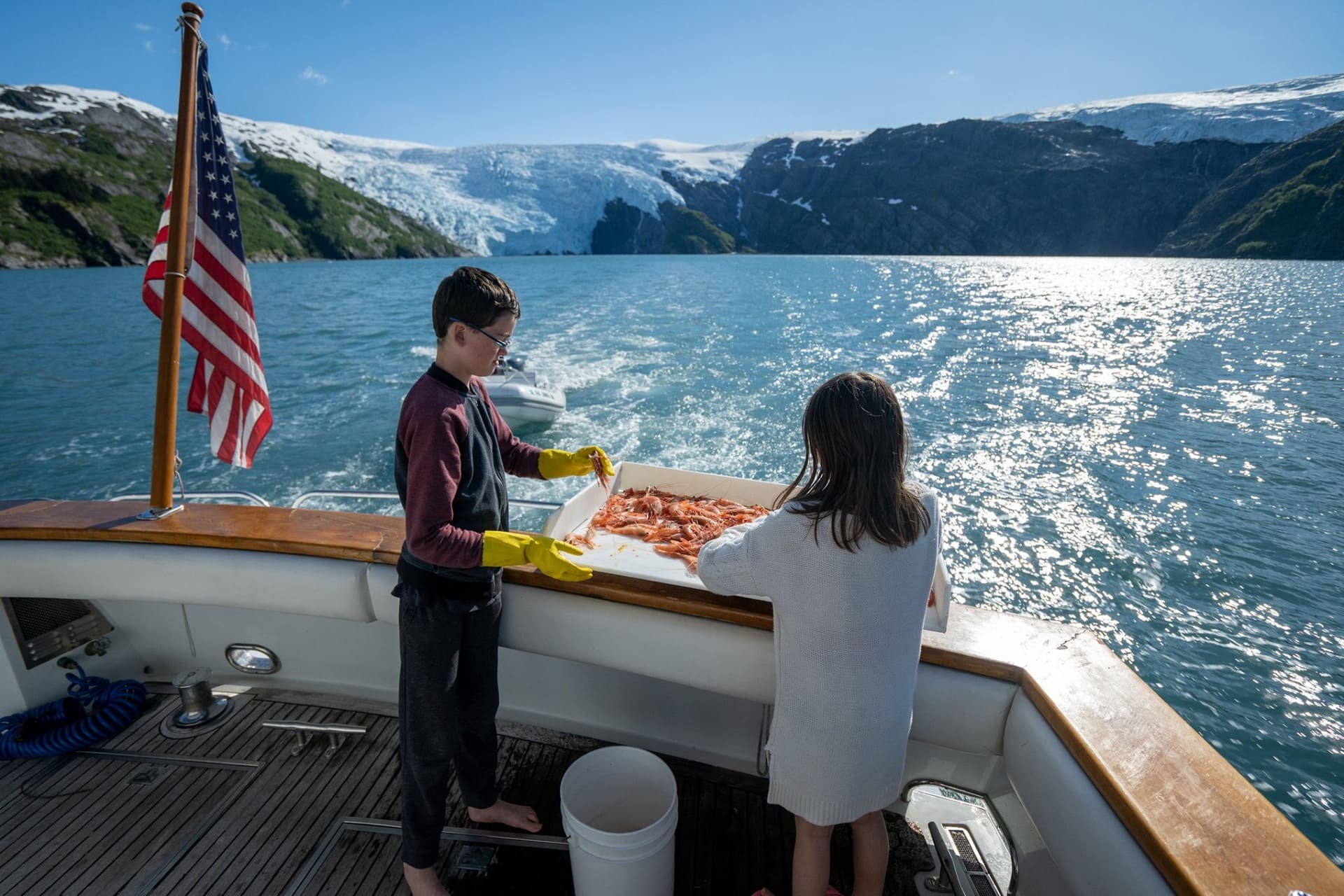 a boy and a girl sorting shrimp at the stern of a ship in Alaskan waters