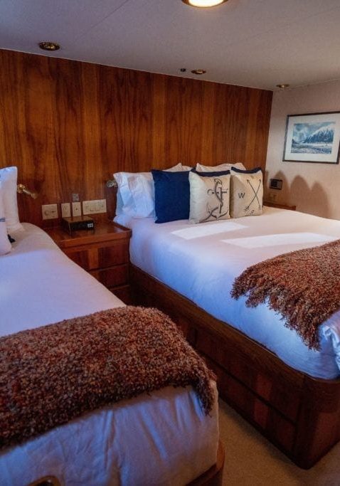 two beds and a night stand in a Stateroom. Nautical themed decor
